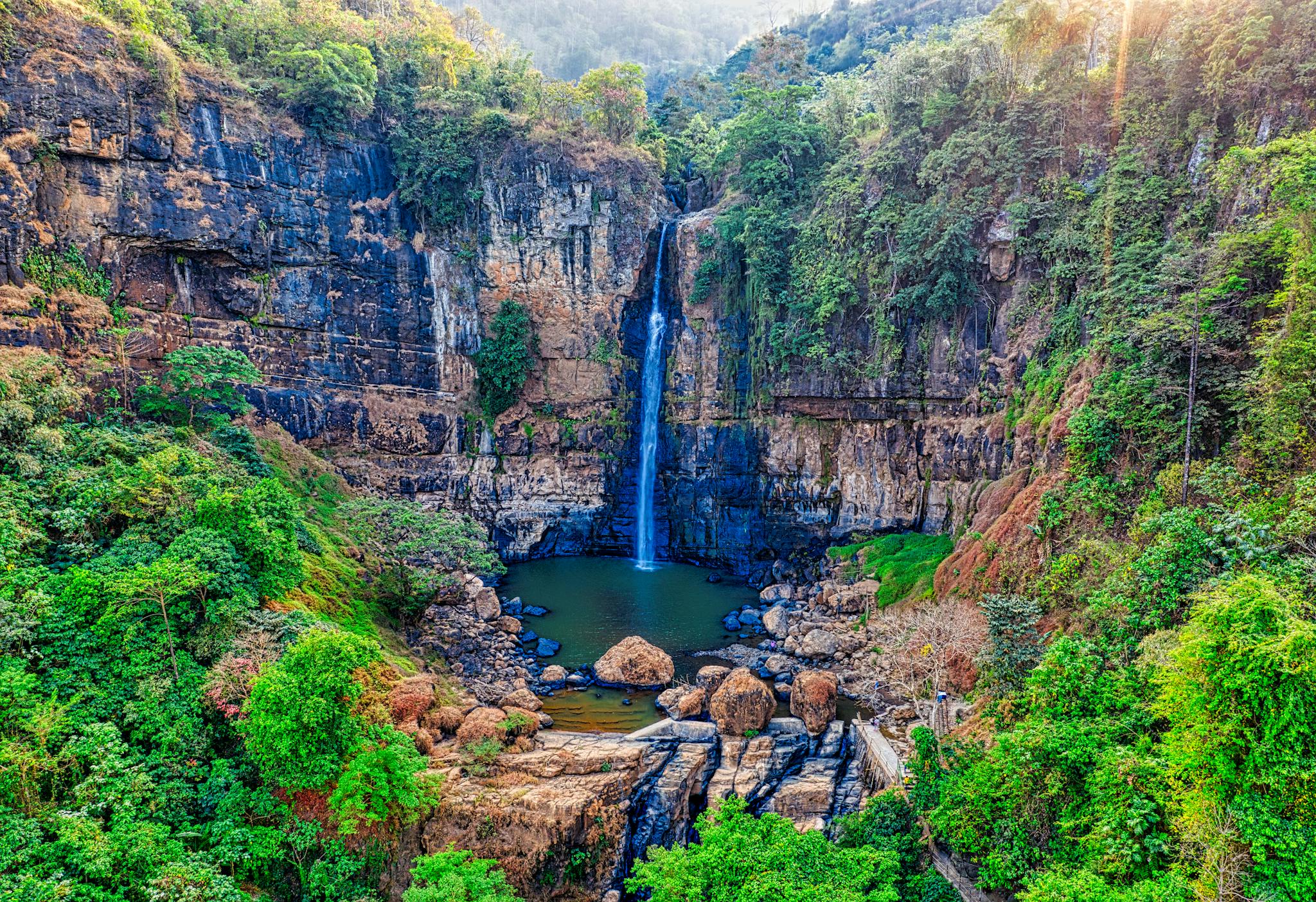 A breathtaking aerial view of a lush forest waterfall in West Java, Indonesia.