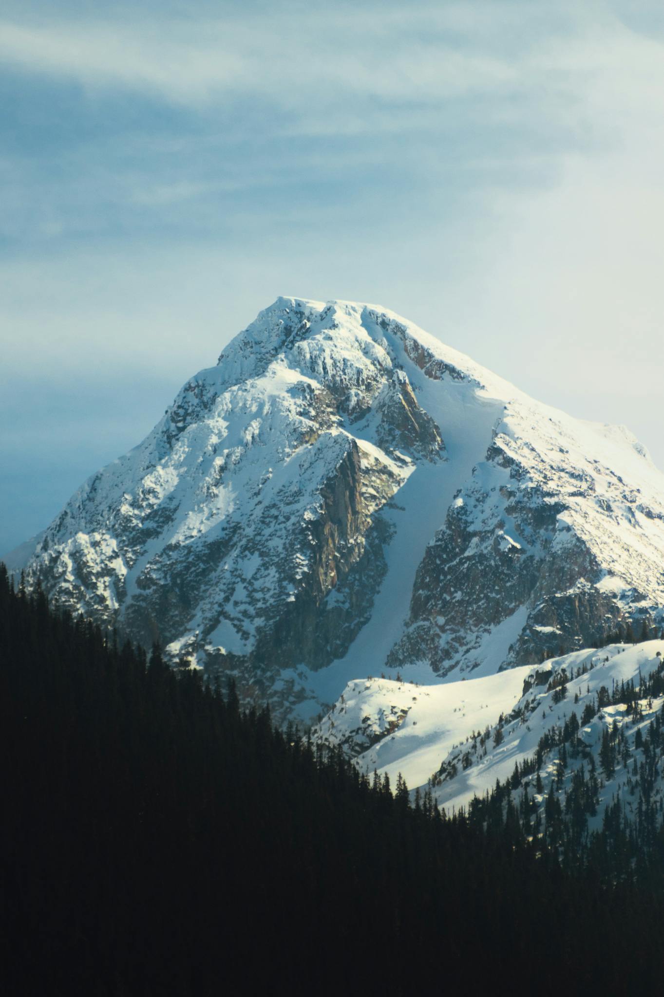 A breathtaking view of a snowcapped mountain peak during winter with a clear sky backdrop.