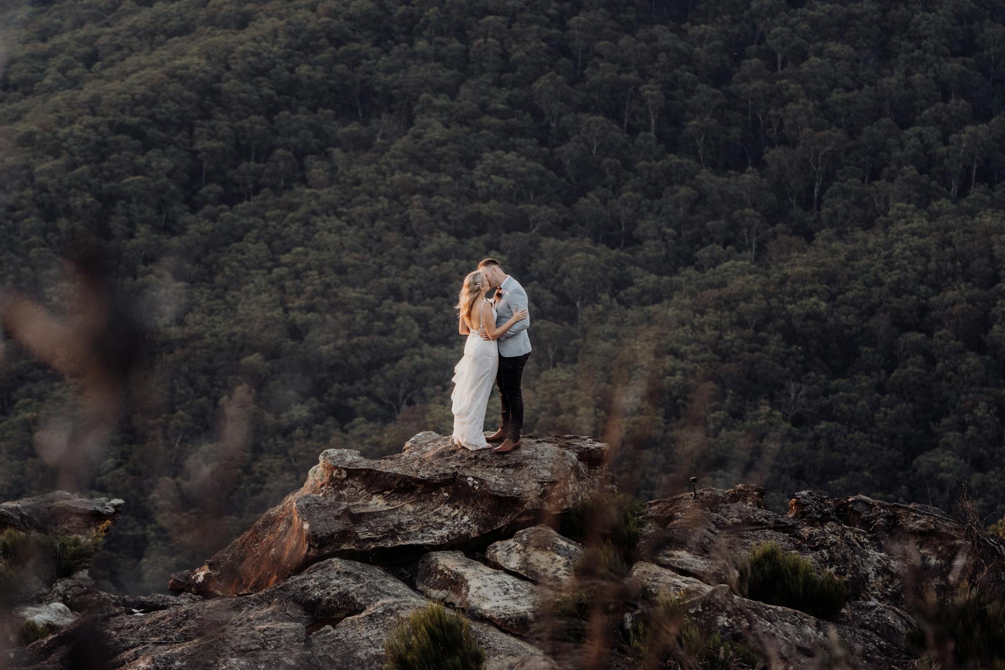 A couple embraces on a rocky outcrop amidst the scenic Blue Mountains, NSW, Australia.