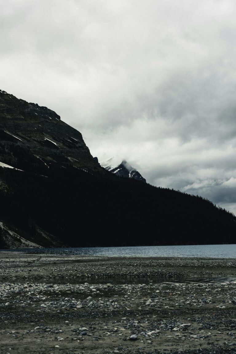 Dramatic cloudy landscape in Banff, featuring a serene lake and rugged mountains.