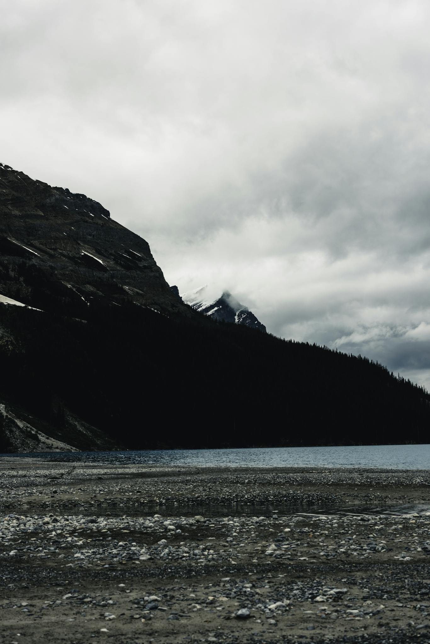 Dramatic cloudy landscape in Banff, featuring a serene lake and rugged mountains.